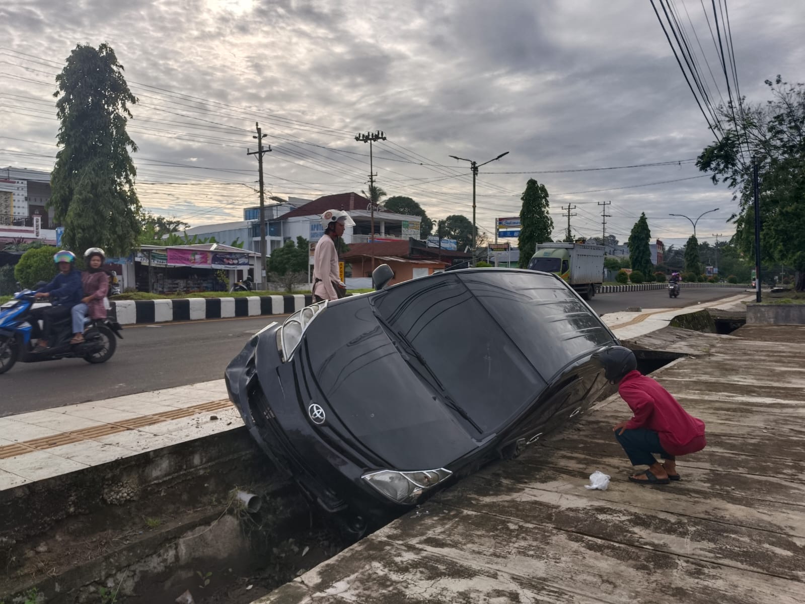 Mobil Berplat Jawa Barat Hantam Trotoar dan Masuk Parit di Jalan Depati Payung Negara